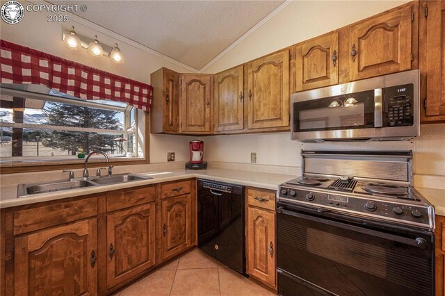 kitchen with dishwasher, lofted ceiling, sink, stove, and light tile patterned floors