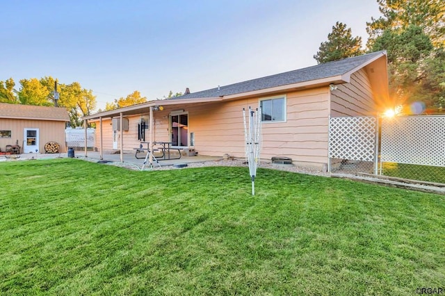 rear view of property featuring an outdoor structure, a patio area, and a lawn