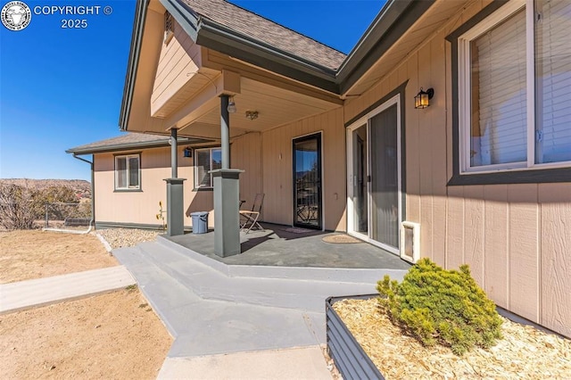 property entrance featuring a patio area and roof with shingles