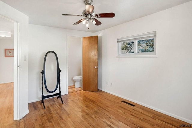 interior space with ceiling fan, ensuite bath, and light wood-type flooring