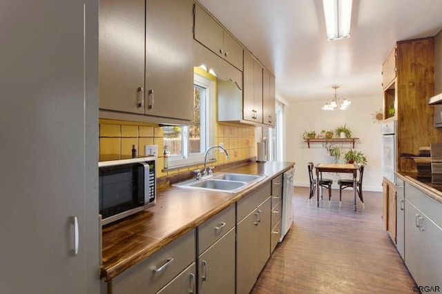 kitchen featuring appliances with stainless steel finishes, decorative light fixtures, tasteful backsplash, sink, and an inviting chandelier