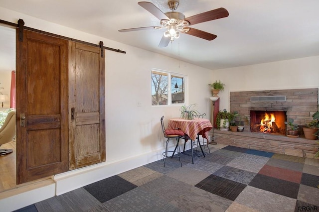 dining area featuring a fireplace, a barn door, and ceiling fan