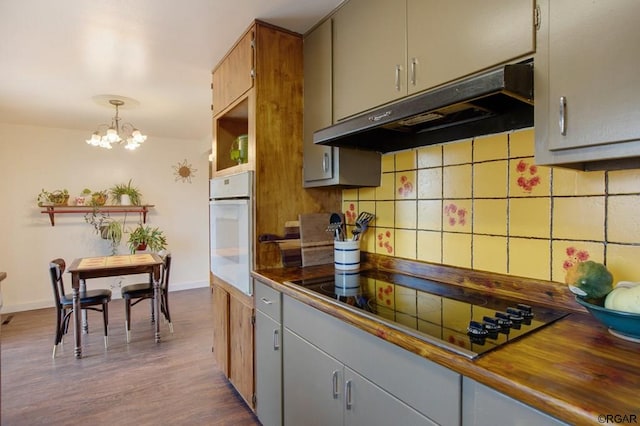 kitchen featuring decorative light fixtures, black electric cooktop, a notable chandelier, hardwood / wood-style flooring, and oven