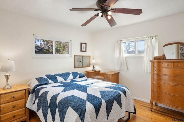 bedroom featuring ceiling fan, multiple windows, and light wood-type flooring