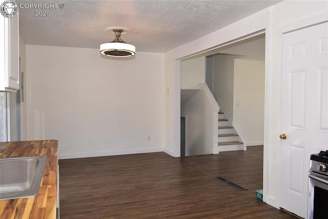 unfurnished dining area with visible vents, stairs, baseboards, and dark wood-style floors
