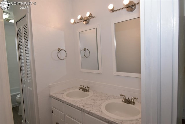 bathroom with double vanity, a sink, and toilet