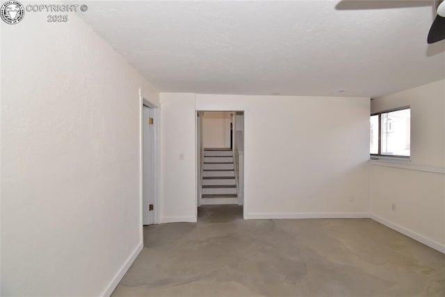 spare room with baseboards, a textured ceiling, ceiling fan, and stairway