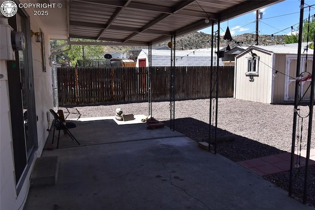 view of patio featuring an outdoor structure, a fenced backyard, and a storage shed