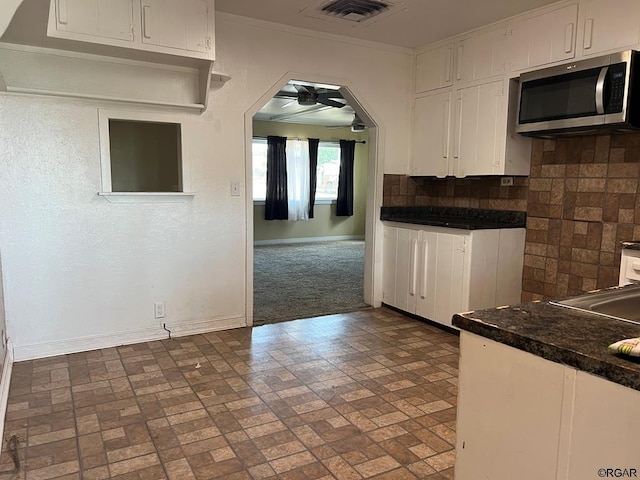 kitchen featuring tasteful backsplash, crown molding, and white cabinets