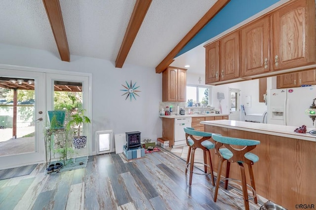 kitchen featuring white appliances, a healthy amount of sunlight, light hardwood / wood-style floors, and a wood stove