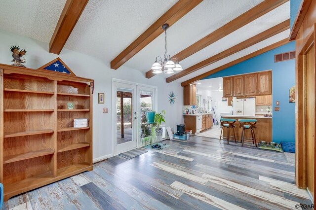 interior space featuring french doors, vaulted ceiling, a textured ceiling, a notable chandelier, and light hardwood / wood-style floors