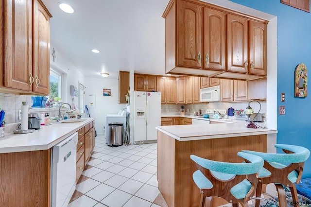 kitchen featuring light tile patterned flooring, sink, kitchen peninsula, white appliances, and decorative backsplash