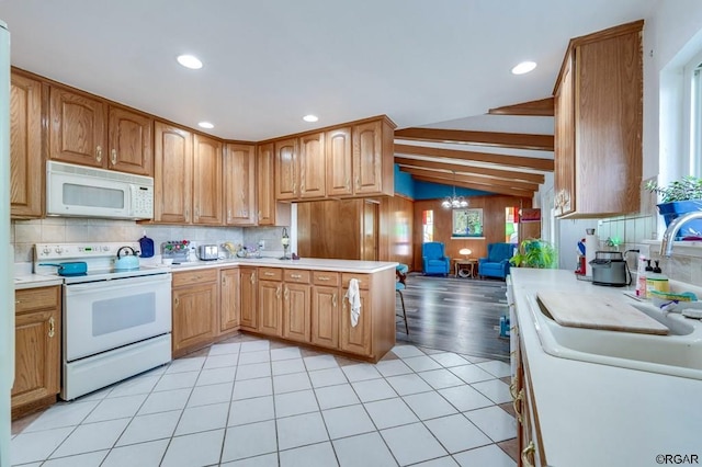 kitchen featuring lofted ceiling, sink, a chandelier, light tile patterned floors, and white appliances