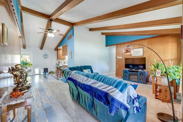 living room with lofted ceiling with beams, ceiling fan, hardwood / wood-style flooring, and a textured ceiling