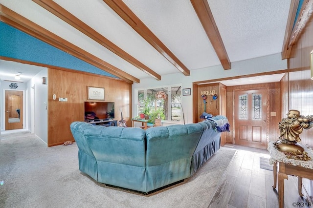 living room featuring lofted ceiling with beams, wood-type flooring, a textured ceiling, and wood walls