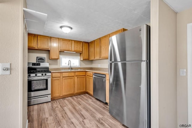 kitchen with appliances with stainless steel finishes, sink, and light wood-type flooring