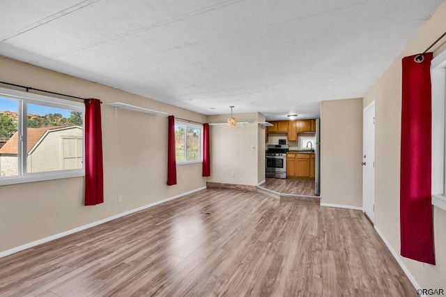 unfurnished living room featuring sink, a wealth of natural light, and light hardwood / wood-style floors