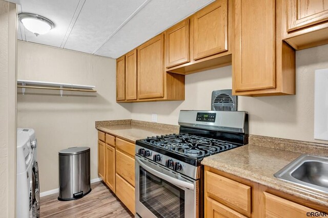 kitchen featuring sink, light hardwood / wood-style flooring, gas stove, and washing machine and clothes dryer