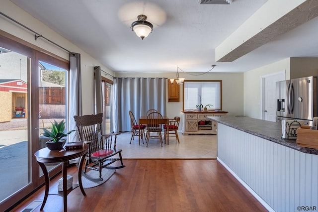 kitchen with an inviting chandelier, wood-type flooring, and stainless steel fridge