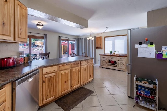 kitchen featuring light tile patterned flooring, stainless steel appliances, decorative light fixtures, and kitchen peninsula