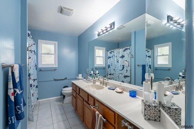 bathroom with a healthy amount of sunlight, toilet, tile patterned flooring, and vanity