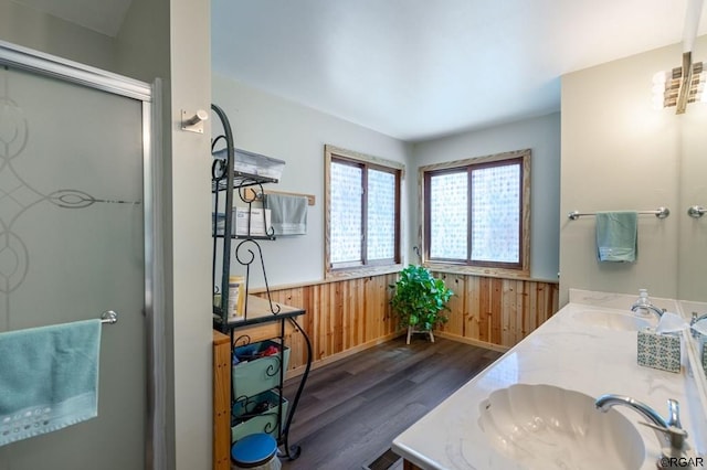 bathroom featuring hardwood / wood-style flooring, vanity, wooden walls, and walk in shower