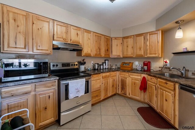 kitchen featuring sink, light tile patterned floors, appliances with stainless steel finishes, pendant lighting, and dark stone counters