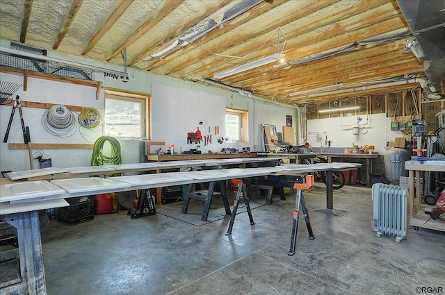 miscellaneous room featuring concrete flooring, radiator, and a workshop area