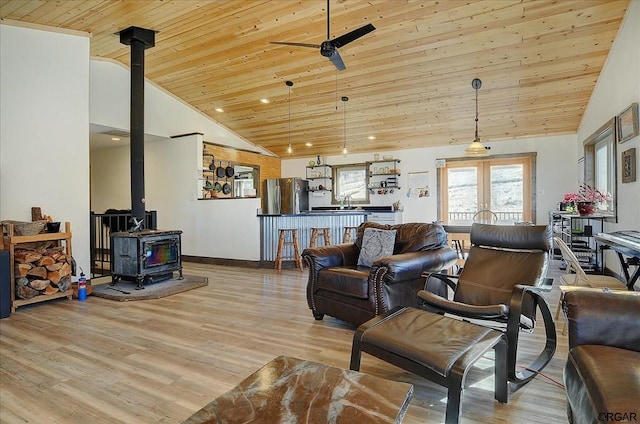 living room with wood ceiling, ceiling fan, high vaulted ceiling, light hardwood / wood-style floors, and a wood stove