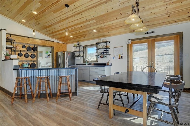 dining area with french doors, lofted ceiling, light wood-type flooring, wooden ceiling, and wet bar