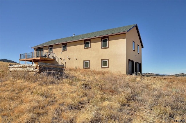 rear view of house featuring a garage and a wooden deck