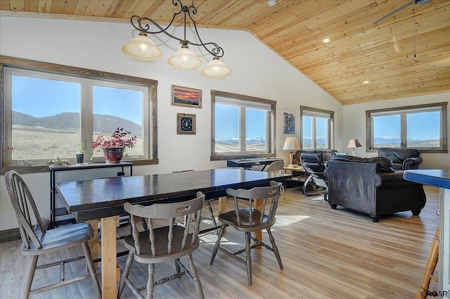 dining space with a mountain view, vaulted ceiling, wooden ceiling, and light hardwood / wood-style floors