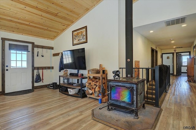 living room with wood ceiling, lofted ceiling, light hardwood / wood-style flooring, and a wood stove