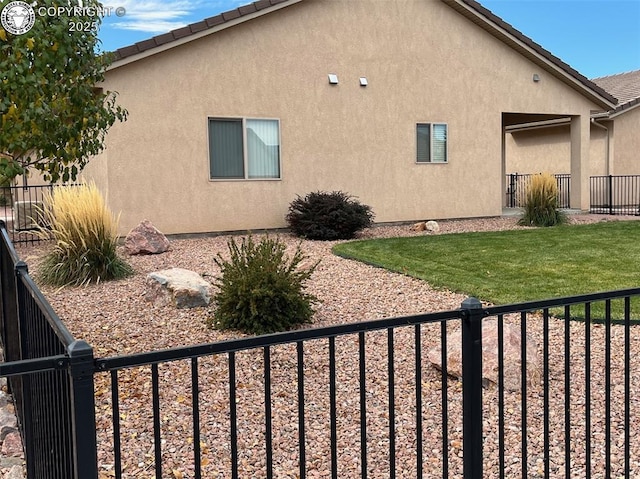 view of property exterior with a tiled roof, a lawn, fence, and stucco siding