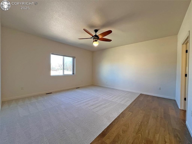 unfurnished room with visible vents, a ceiling fan, a textured ceiling, wood finished floors, and baseboards