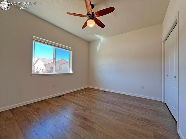 unfurnished bedroom featuring dark wood finished floors, a closet, visible vents, ceiling fan, and baseboards