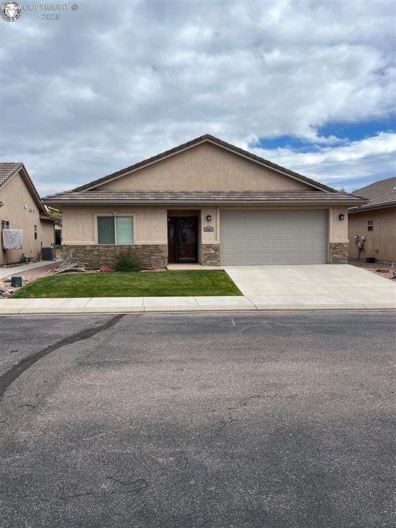 ranch-style house featuring stone siding, an attached garage, concrete driveway, and stucco siding