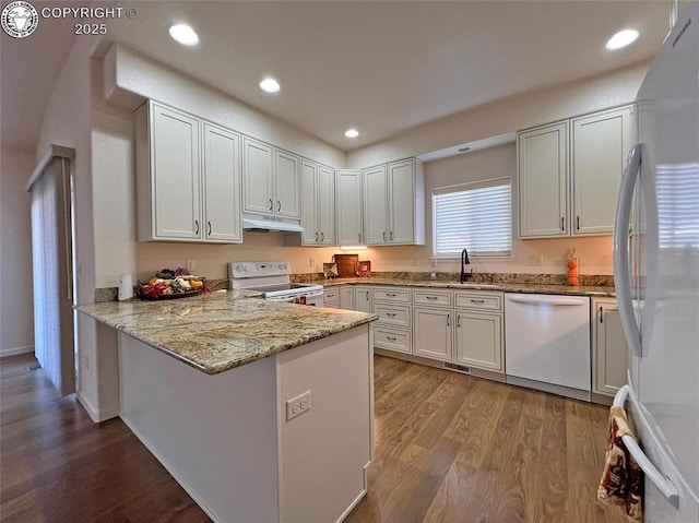 kitchen with under cabinet range hood, a peninsula, white appliances, white cabinets, and light stone countertops