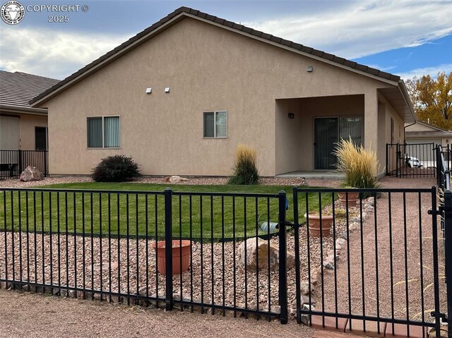 view of side of home with a yard, fence, a tiled roof, and stucco siding