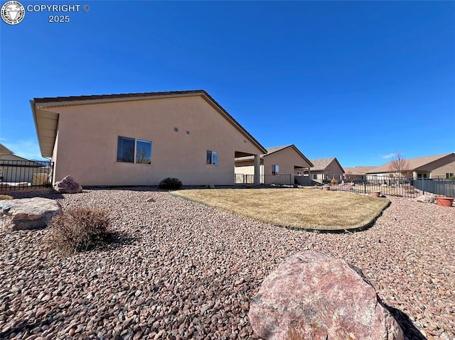 rear view of property with a fenced backyard and stucco siding