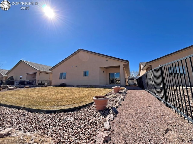 back of property with a yard, fence, and stucco siding