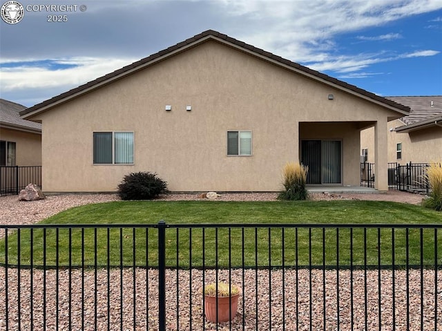 rear view of property with a lawn, fence, and stucco siding