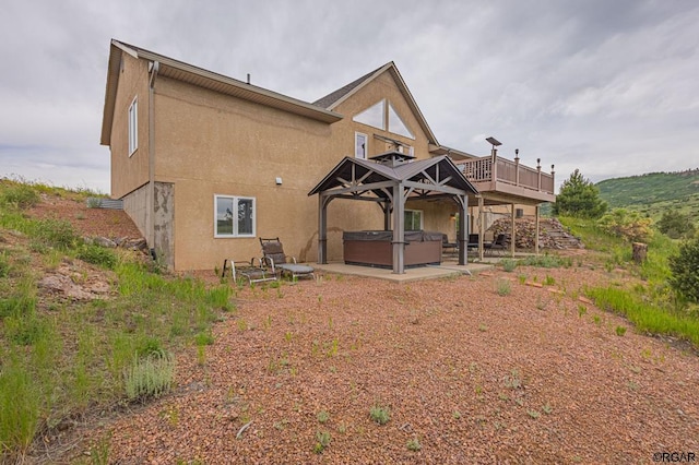 rear view of house featuring a hot tub, a deck, and a patio area