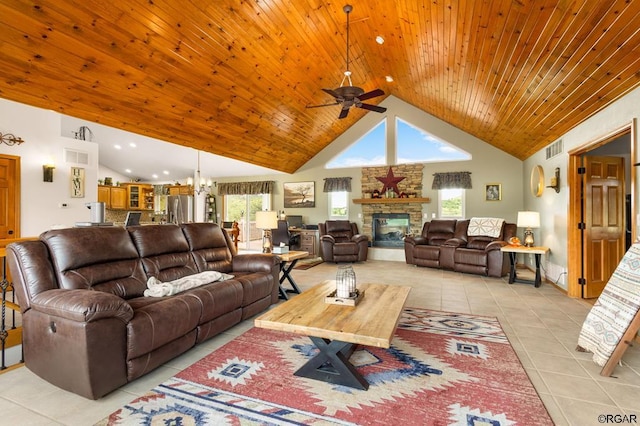 living room featuring a wealth of natural light, a stone fireplace, light tile patterned floors, and high vaulted ceiling