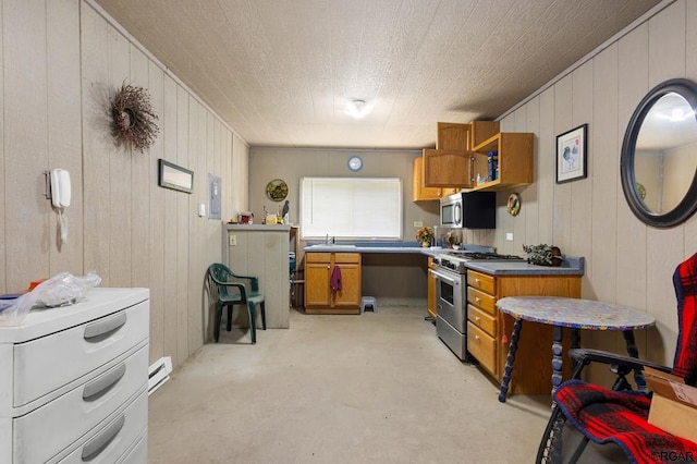 kitchen featuring appliances with stainless steel finishes, a baseboard heating unit, sink, and wooden walls