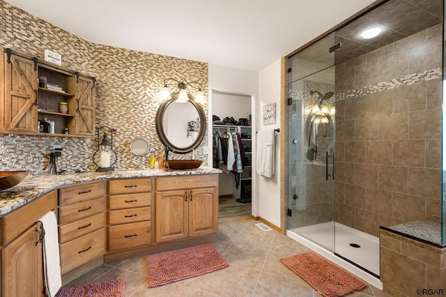 bathroom with tasteful backsplash, vanity, tile patterned flooring, and an enclosed shower