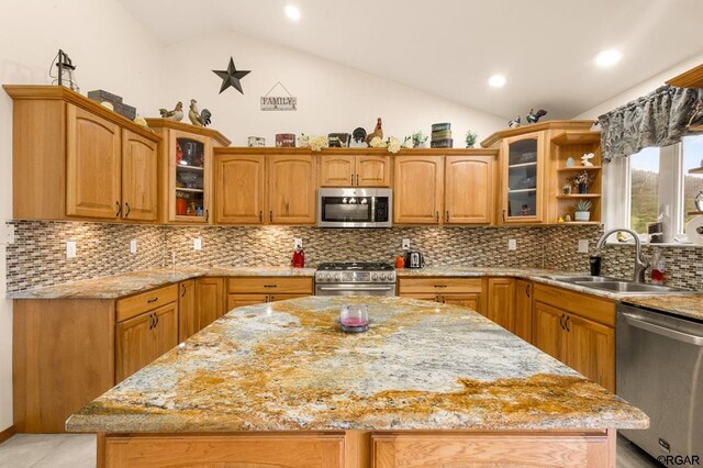 kitchen with vaulted ceiling, sink, a center island, stainless steel appliances, and light stone countertops