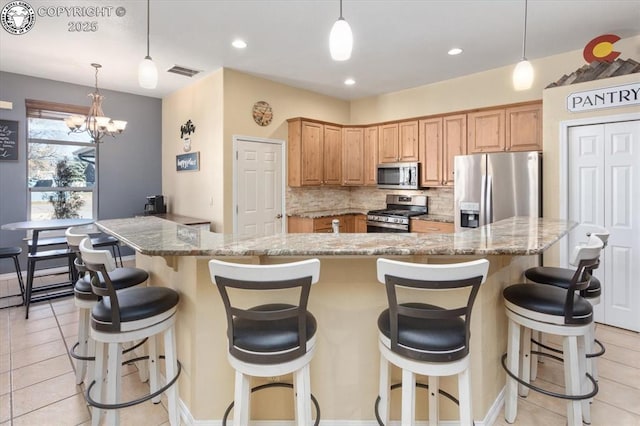 kitchen featuring pendant lighting, backsplash, light stone countertops, and appliances with stainless steel finishes