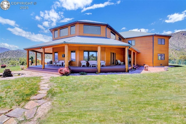 back of house featuring metal roof, a patio, a deck with mountain view, a yard, and log veneer siding