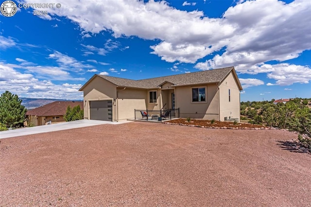 ranch-style house featuring driveway, an attached garage, and stucco siding